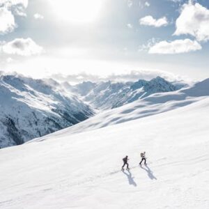 Two-hikers-trekking-uphill-in-snow-during-Mount-Kenya-hikes-with-scenic-snowy-peaks-in-the-background