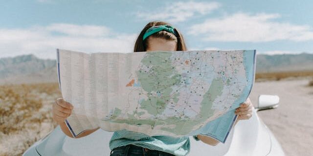 Solo woman traveler reviewing a map on the roadside Solo-woman-traveler-reviewing-a-map-on-the-roadside