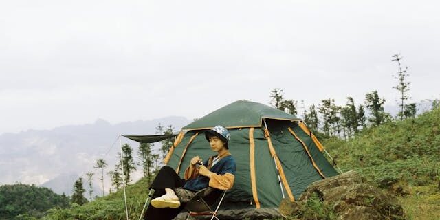 Introvert traveler relaxing at a campsite, admiring a mountain view Introvert-traveler-relaxing-at-a-campsite-admiring-a-mountain-view
