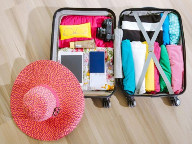 Essential items for women travelers packed in a suitcase, prepared for a trip Essential-items-for-women-travelers-packed -n-a-suitcase-prepared -or-a-trip