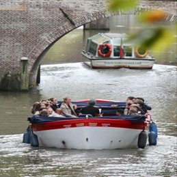Tourists-on-a-canal-boat-passing-under-a-brick-bridge
